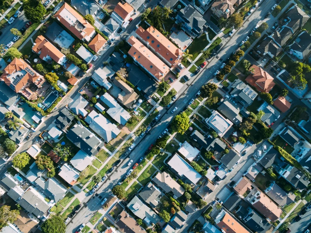 An aerial view of a residential neighborhood showcases rows of houses, roads, and lush green trees, illustrating the harmonious balance achieved through meticulous resource consent planning. The change in Christchurch Development Contributions will have an impact on property development in Christchurch.