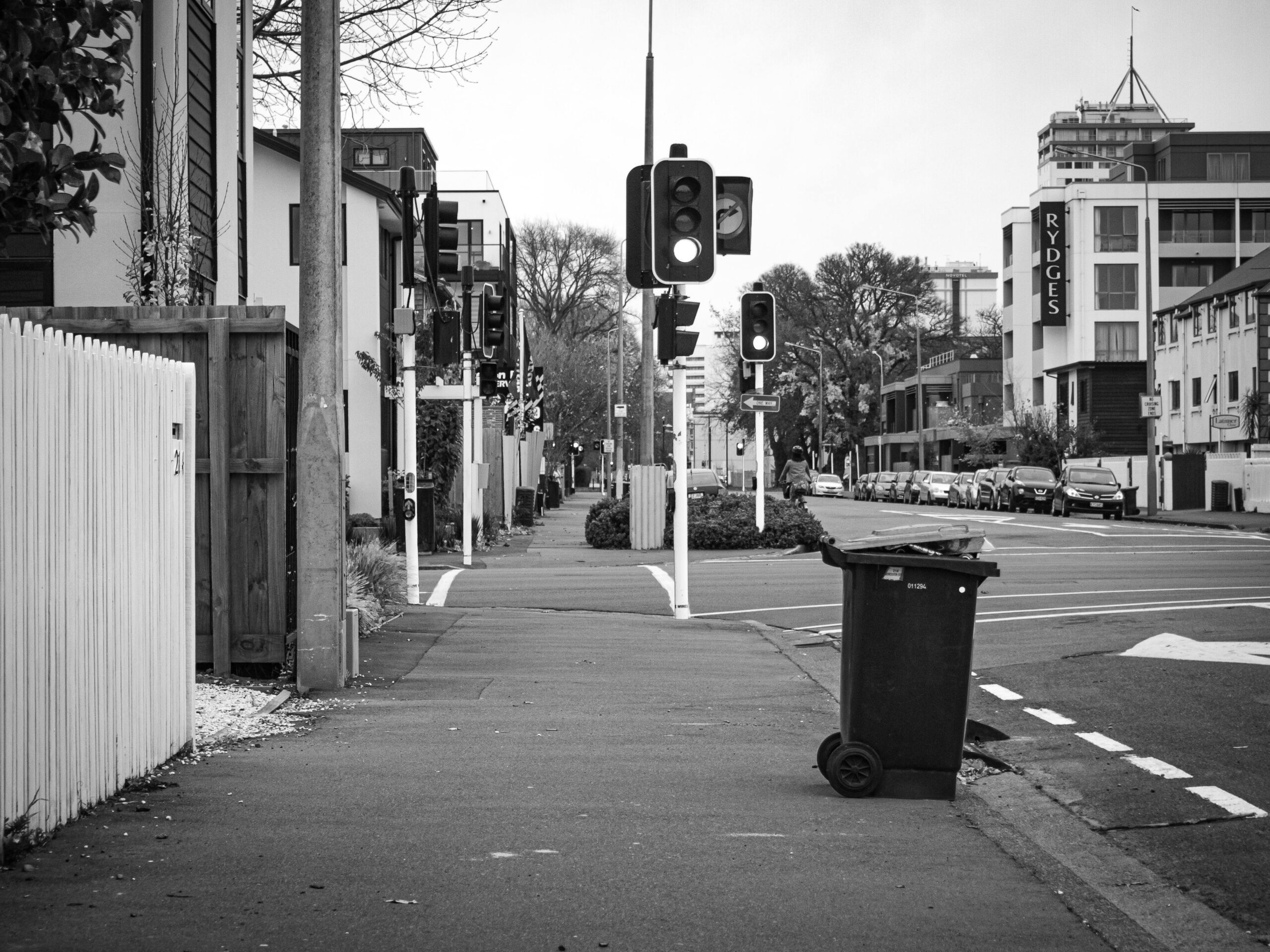 black and white image of a street corner in christchurch new zealand with a recycle bin outside