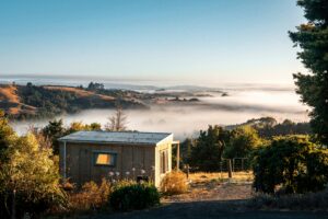 Image shows a small detached residential dwelling on a hillside site in Canterbury, New Zealand.